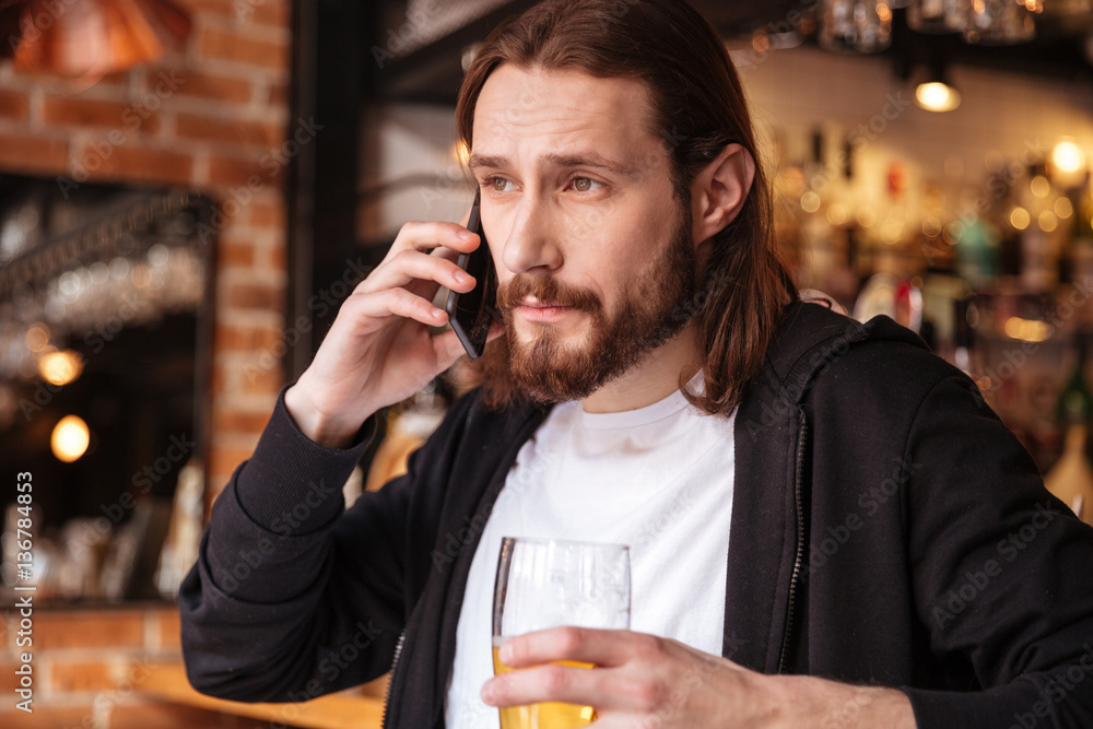 Cool bearded man talking on phone near the bar