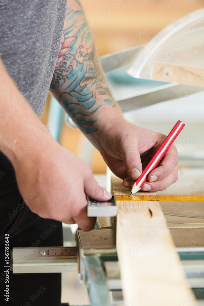 Carpenter measures length of a wood plank before sawing Carpenter measures length of a wood plank before sawing