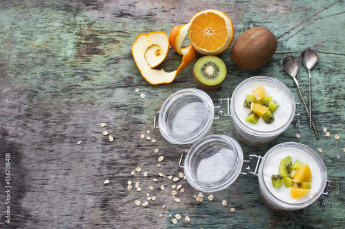 Breakfast yogurt with oatmeal and orange Kiwi fruit on a wooden background top view