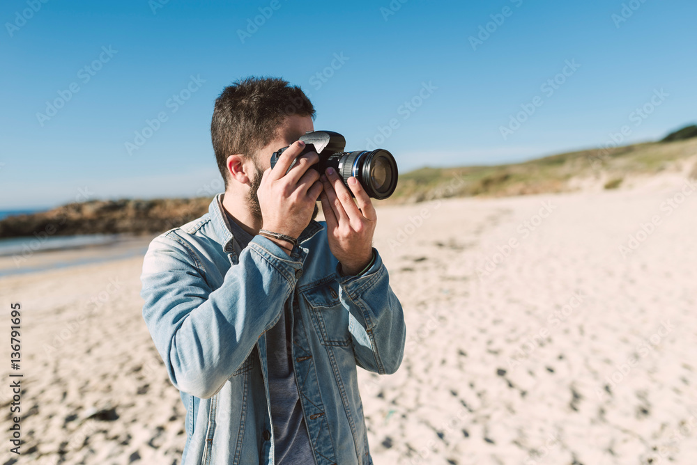 Casual young man taking a photo on beach