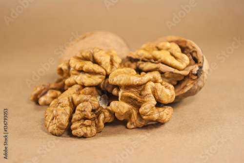Walnut kernels and whole walnuts on kraft paper, close up, horiz