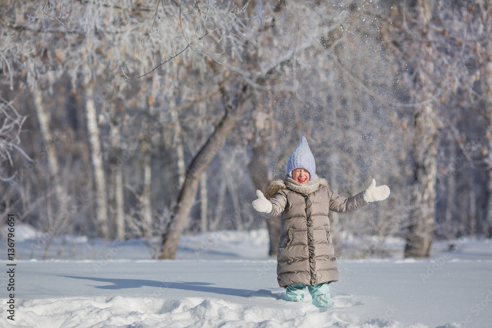 Little girl in grey jacket plays with snow in winter forest Little girl in grey jacket plays with snow in winter forest
