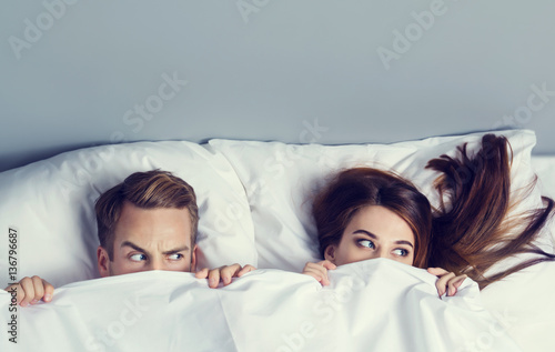 Playfull couple peeping from bedsheet photo