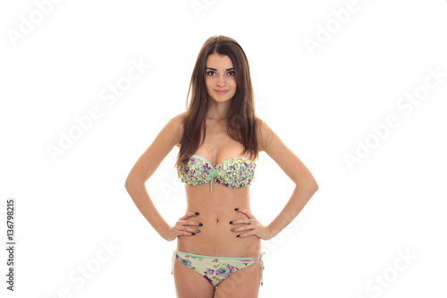 adorable young woman with big natural breasts in swimsuit with floral pattern looking at the camera and smiling isolated on white background