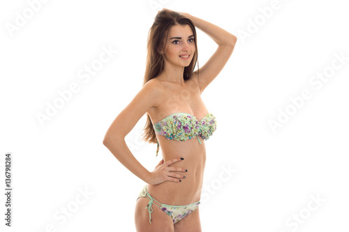 cheerful young woman with big natural boobs in swimsuit with floral pattern posing and smiling isolated on white background