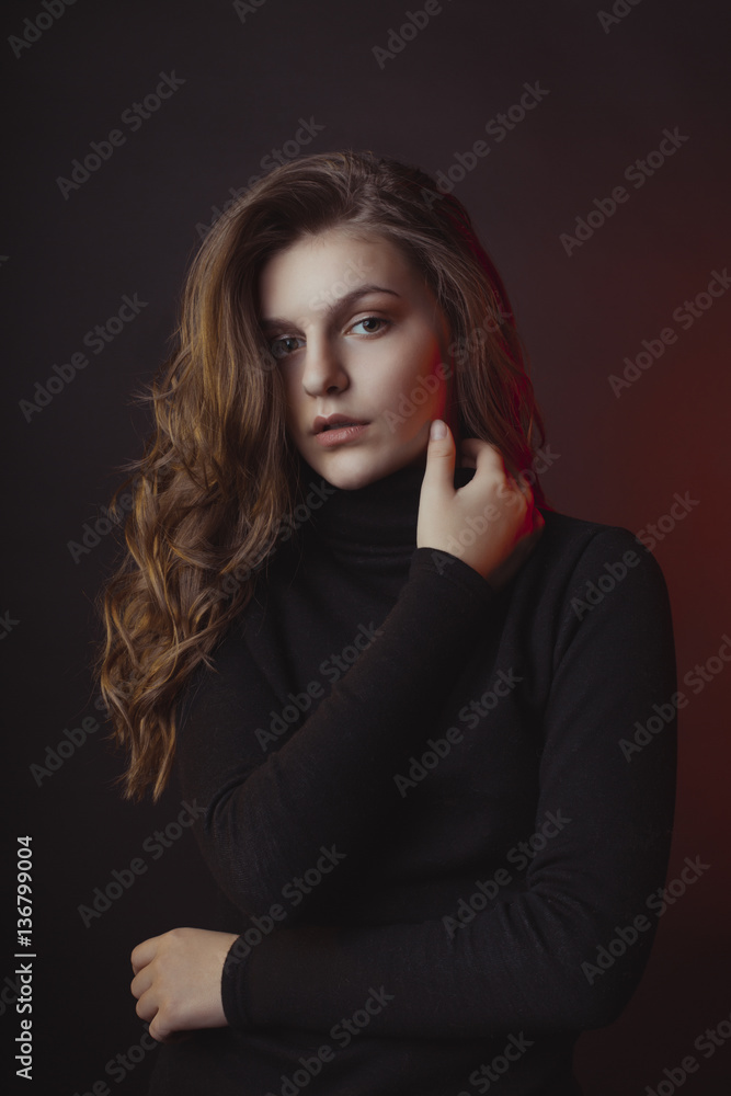 Lovely young woman posing in sweater at dark room Lovely young woman posing in sweater at dark room