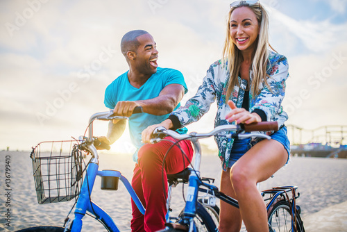 happy couple riding bikes together during sunset at santa monica california