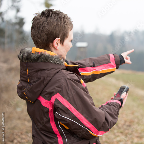 female geocacher hiking with gps photo