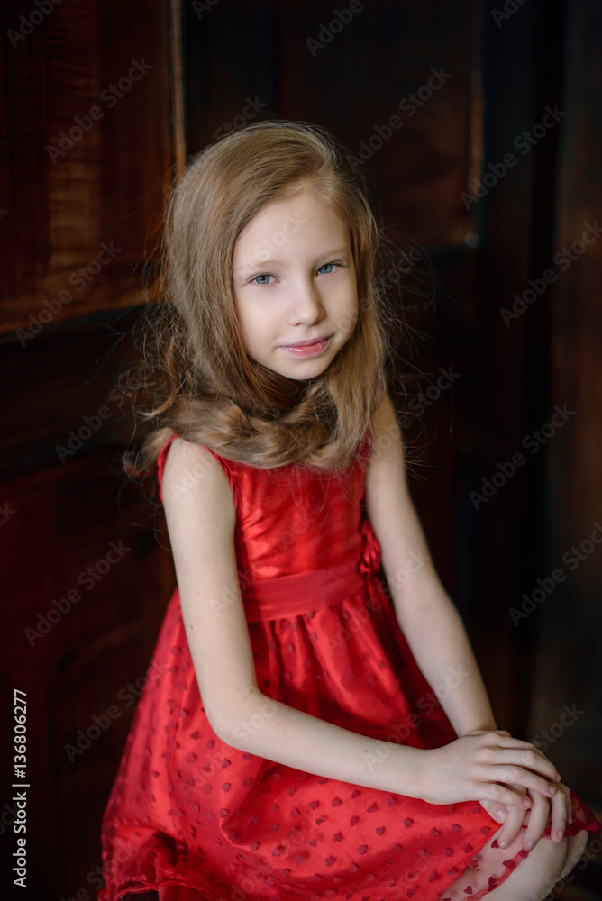 Fototapeta premium Portrait of a cute young redheaded girl sitting on a chair