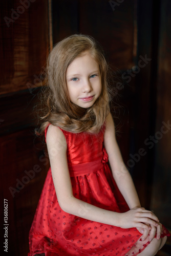 Portrait of a cute young redheaded girl sitting on a chair