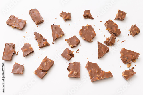Broken milk chocolate pattern, top view flat lay on background