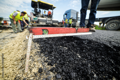 Heavy duty road building. Hot Asphalt being laid and measured fo