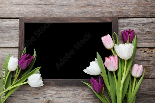 Bouquet of tulips with frame on grey wooden table
