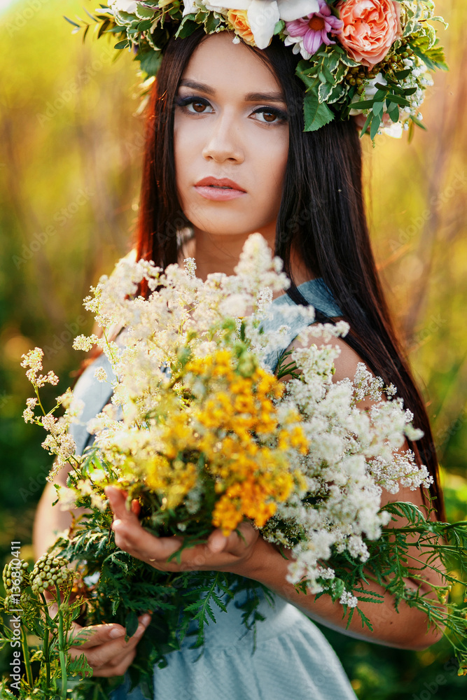 Beautiful woman with flower wreath on head with flower in hand