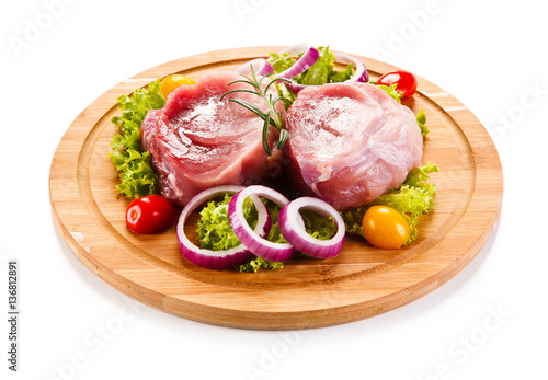 Raw meat on cutting board and vegetables 