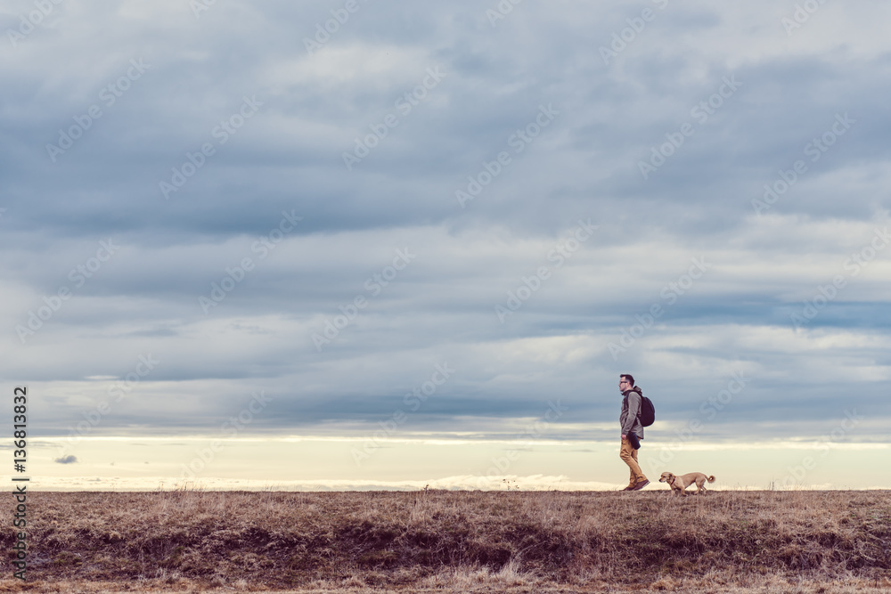 Hiker and dog walking in grassland
