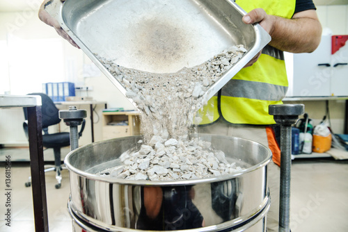 On site road testing laboratory. Placing sample of gravel into a