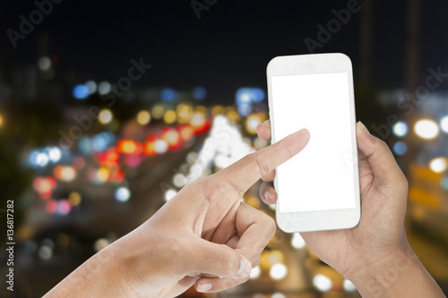 Closeup of pointing hand and hand holding smart phone with blank screen for your text with night light bokeh