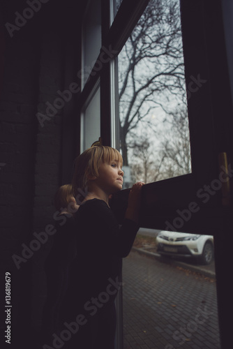 little girl in a black suit looks out the window