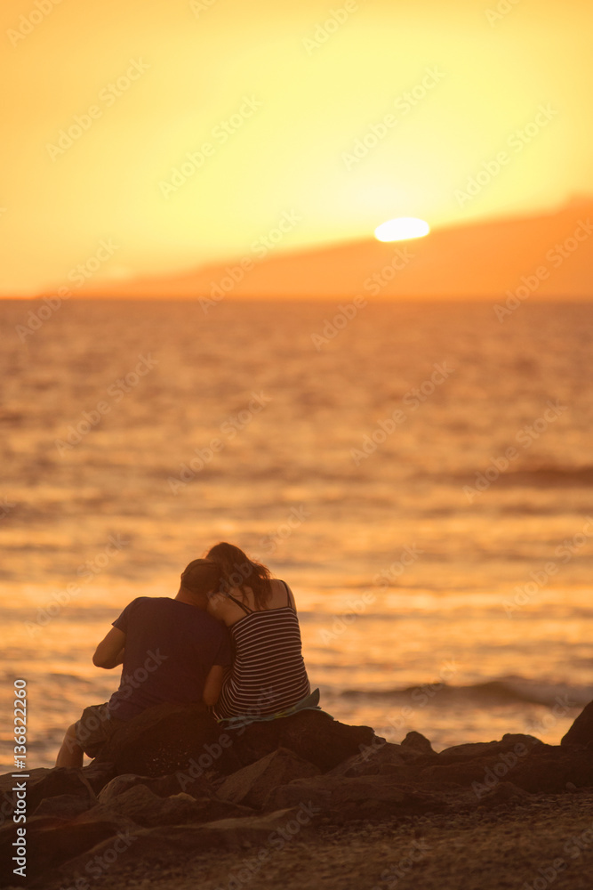 Couple in love taking pictures on the beach at sunset. 