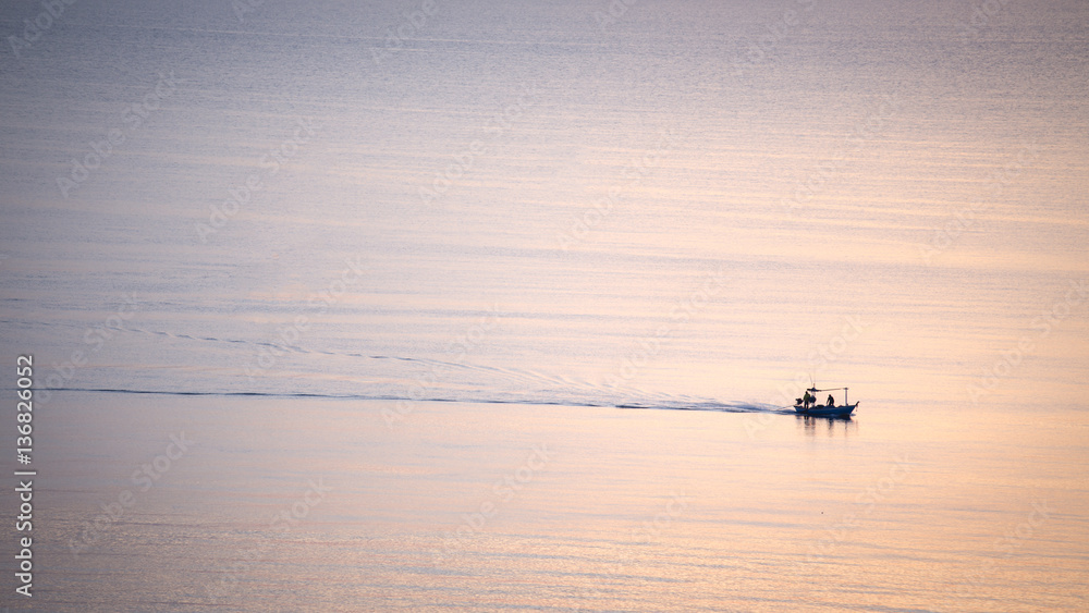 Fototapeta premium silhouette sunrise of minimal fishery boat sail on calm sea