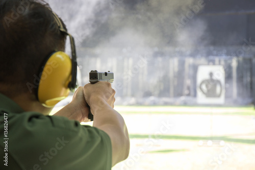 man shooting automatic  pistol to target in shooting range photo