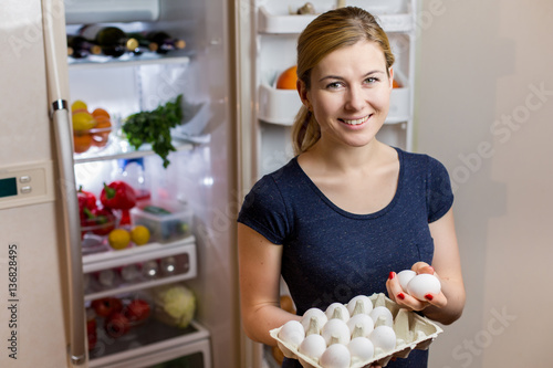 Healthy Eating Concept. Diet. Beautiful Young Woman near the Fridge with eggs. healthy food. Fruits and Vegetables in the Refrigerator. Vegan food