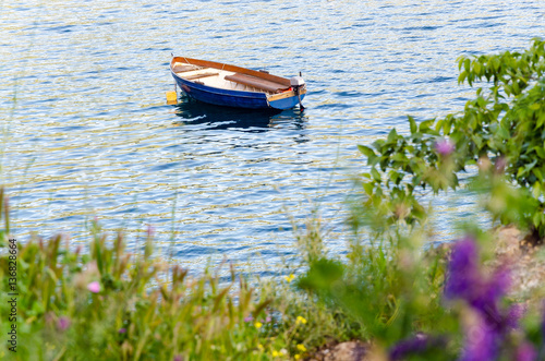 Fotografie, Obraz Empty blue boat moored in crisp clear waters of lake or sea