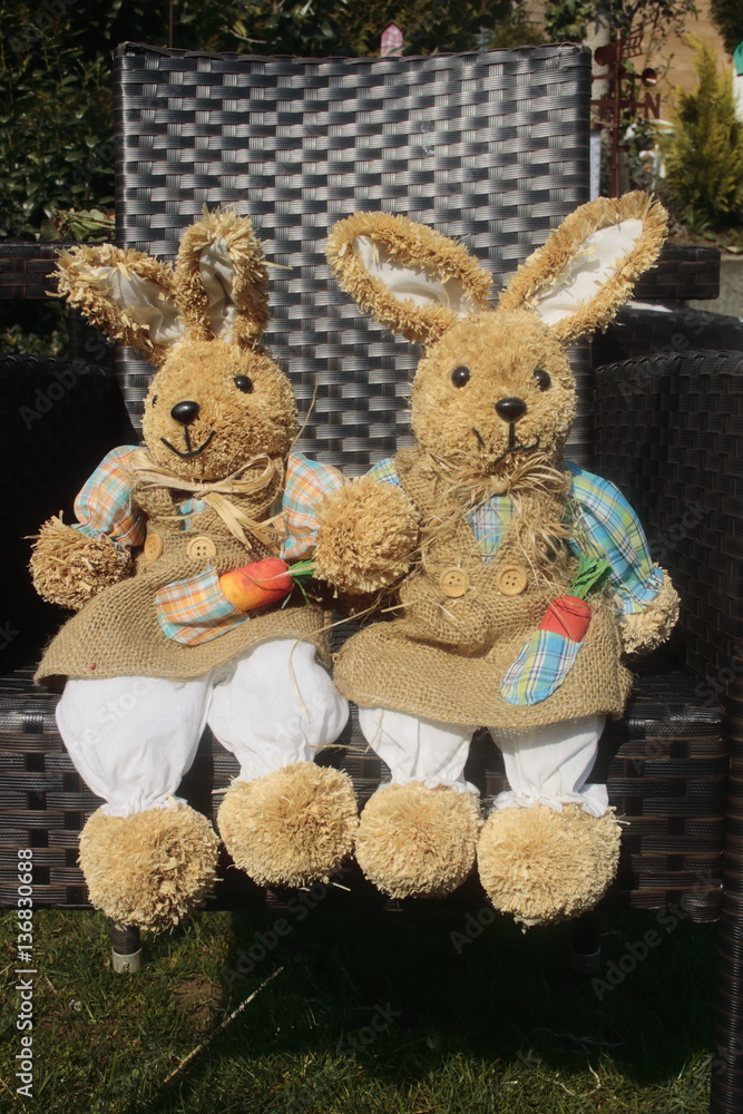 Fototapeta premium Osterhase aus Stroh sitzt auf einem Stuhl