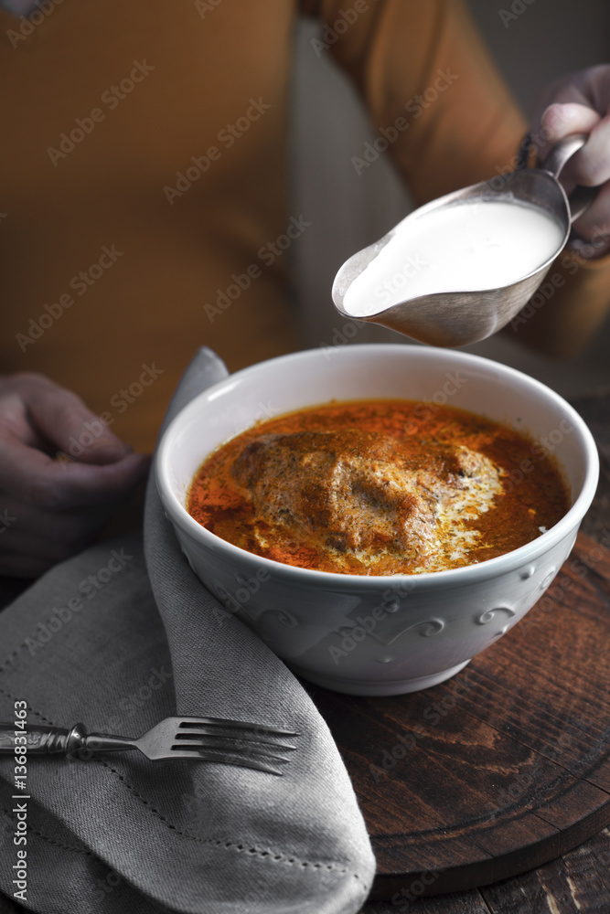 Butter chicken, sauce-boat with cream and a woman at the table Butter chicken, sauce-boat with cream and a woman at the table