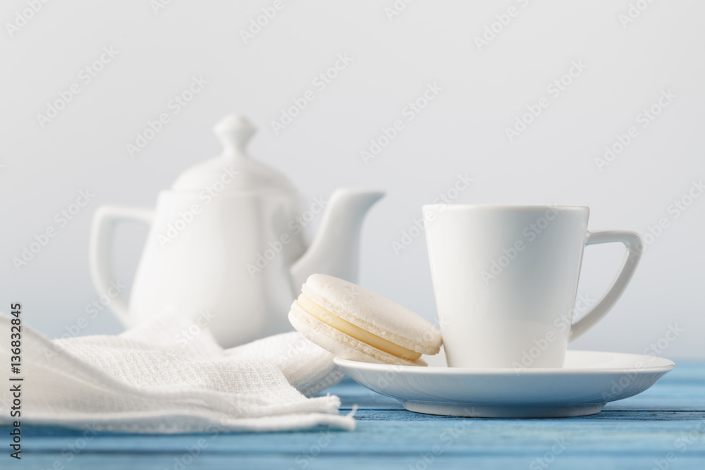 White parcelain cup with tea and one macaroon White parcelain cup with tea and one macaroon
