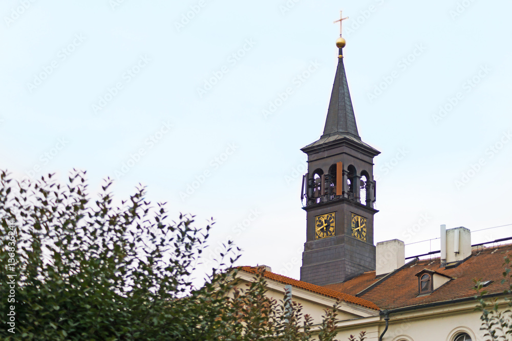 Black tower with a clock and a Catholic cross. Prague.