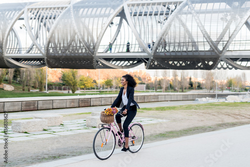 Business black woman riding a vintage bicycle in the city