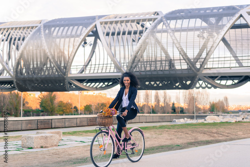 Business black woman riding a vintage bicycle in the city