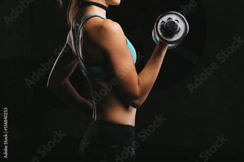 Sport fitness woman training on dark background. Beautiful body