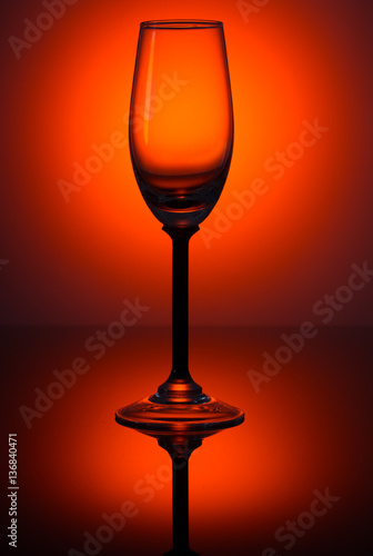Empty wine glass on a rich dark red gradient background.