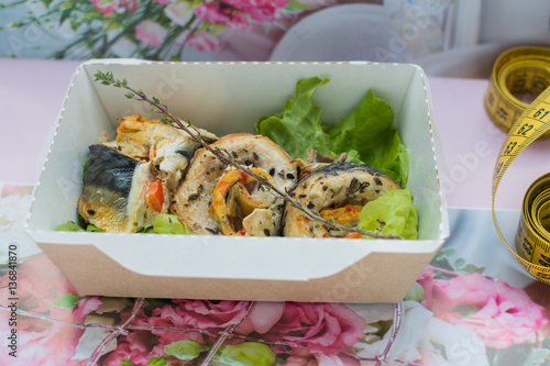 Fried fish in a craft box on a flower background cloth with a centimetric tape photo