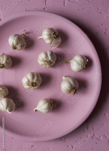 Healthy small garlic in pink plate top view
