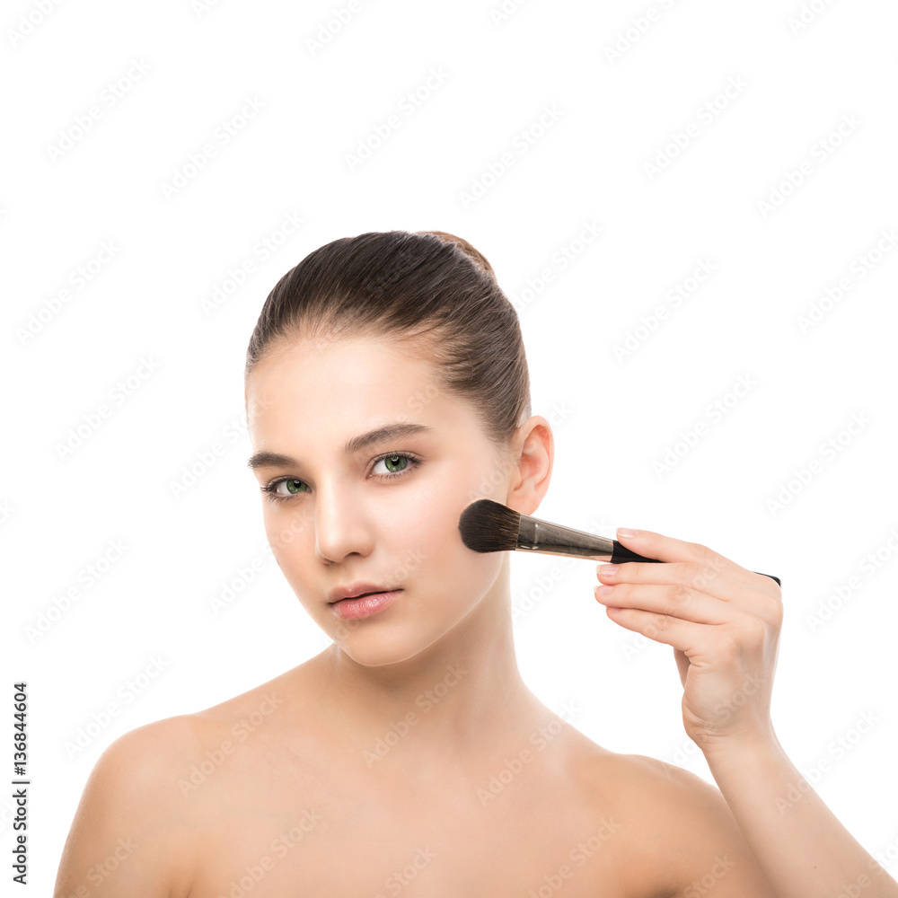 Portrait of beautiful young brunette woman with clean face. Beauty spa model girl with perfect fresh clean skin applying cosmetic brush. Youth and skin care concept. Isolated on a white background.