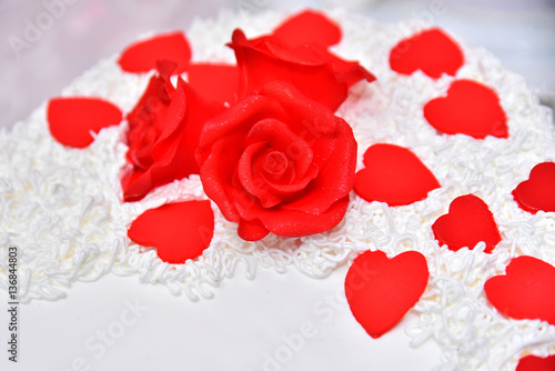 Sweet cakes in the form of red roses decorate the wedding cake with more decorative twigs of white cream. Photographed at a wedding in Novi Sad, Serbia.