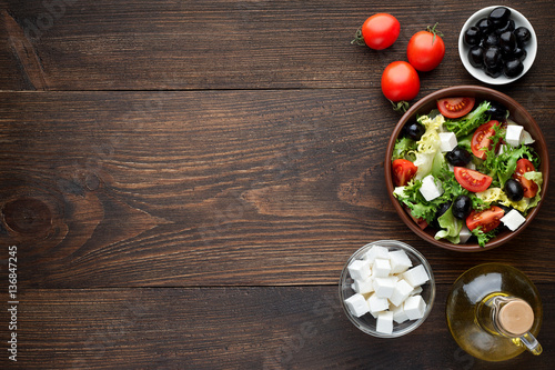 Bowl of fresh salad with feta for healthy eating on wooden table.