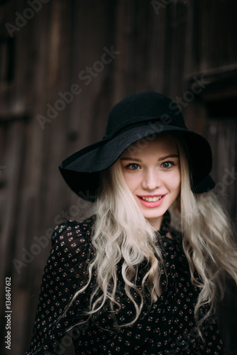 Beautiful attractive and stylish girl wearing black hat standing posing in city. Nude makeup, best daily hairstyle and great fashion glamour country style.
