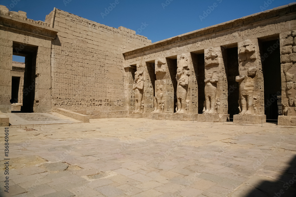 wall and colonnade of landmark Egyptian Temple of Ramses or Ramesses III at Medinet Habu, monument with carving figures and hieroglyphs, in Luxor, Egypt, Africa
