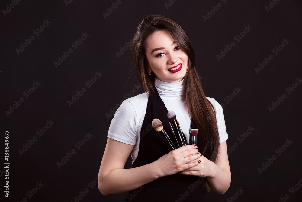 Makeup artist with brushes in hand on a black background Makeup artist with brushes in hand on a black background