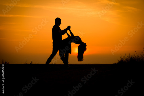 silhouette teenager lovers couple with sun between on sunset dusk sky background: black shadow hand drawn of people hug and kiss people:passion in love concept:decoration,design,valentines © icephotography