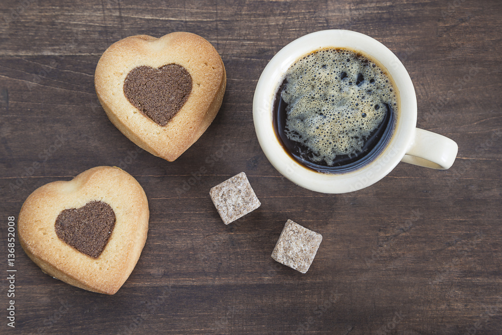 cup of coffee, cookies shaped heart and lumps of sugar on dark wooden background top view cup of coffee, cookies shaped heart and lumps of sugar on dark wooden background top view