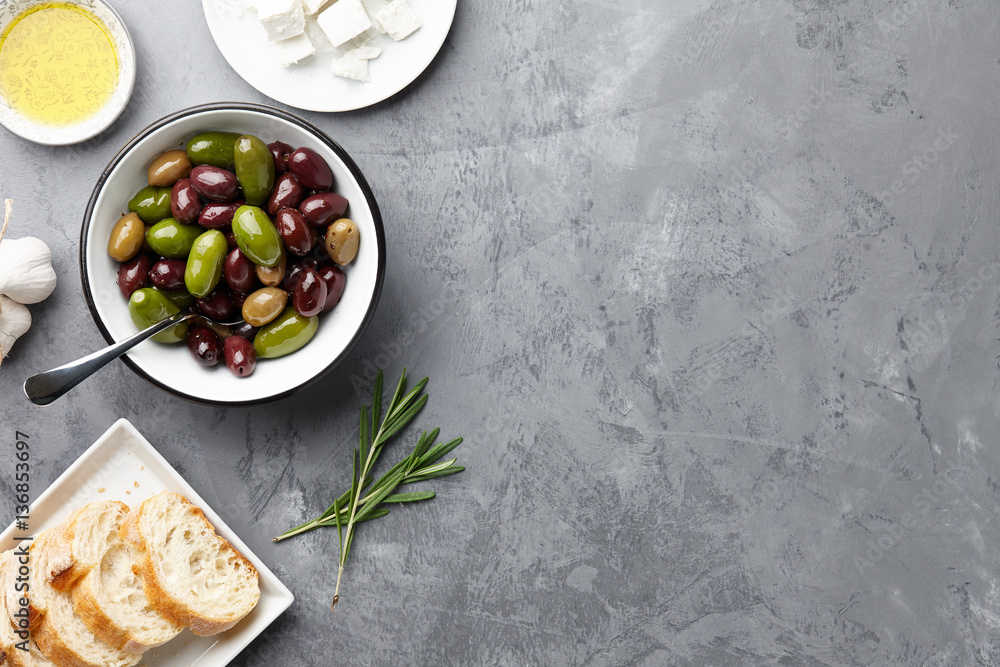 Φωτογραφία Fresh olives, feta cheese, rosemary, olive oil and ciabatta bread on gray stone