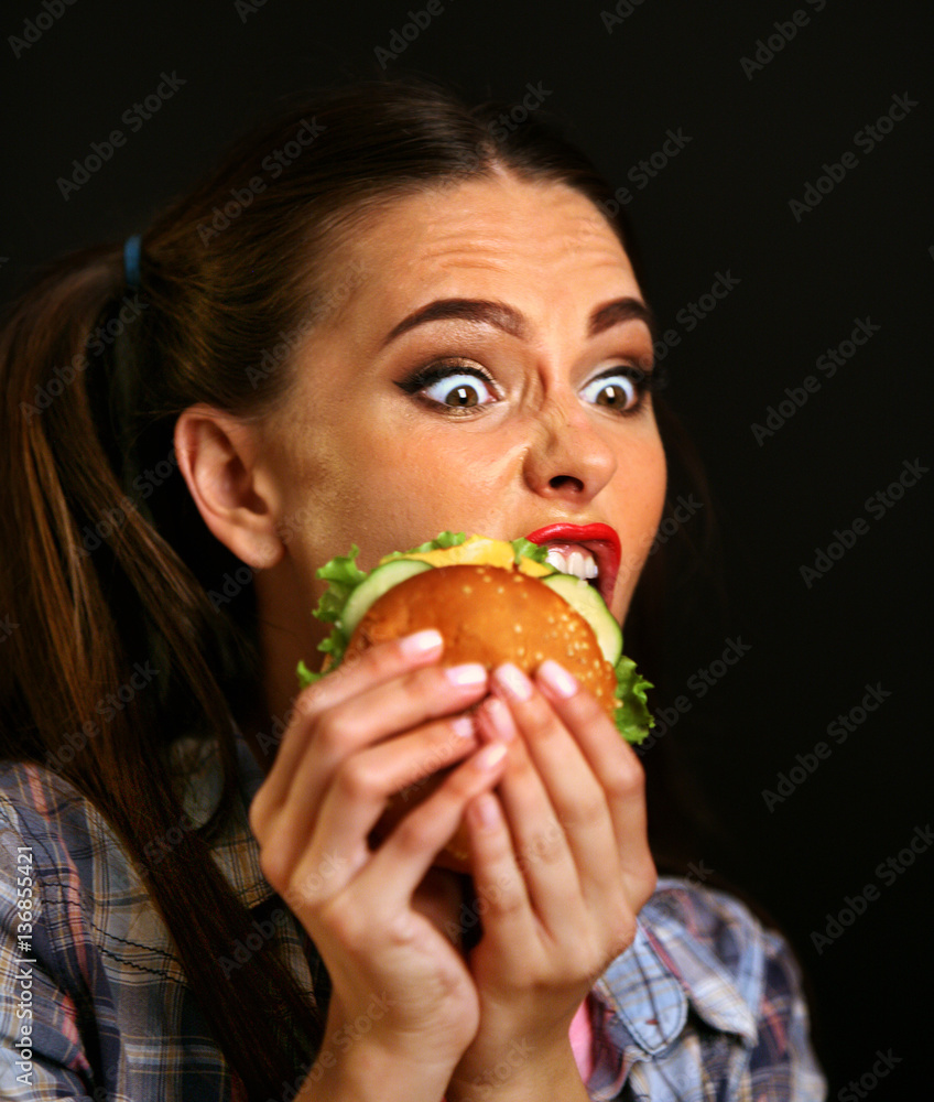 Woman eating hamburger. Girl wants to eat burger. Student consume fast food. Portrait of person with good appetite have greedily dinner delicious sandwich on a black background. Woman eating hamburger. Girl wants to eat burger. Student consume fast food. Portrait of person with good appetite have greedily dinner delicious sandwich on a black background.