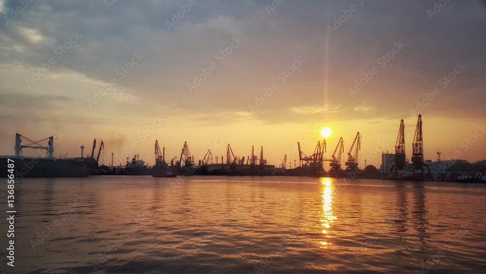 Fire sunset over the sea horbour in Varna.port. Silhouttes of the cranes.