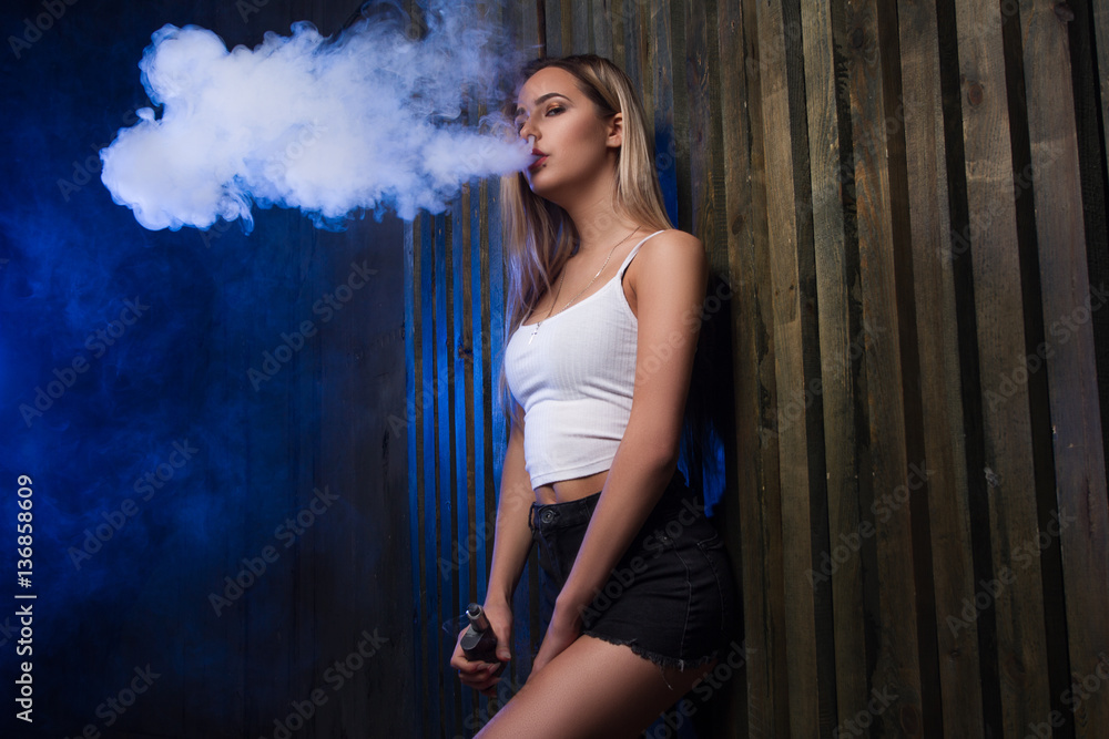Cloud of smoke. girl and smoking electronic cigarette. Smoking vape mod in a sexy way. foto de Stock | Stock